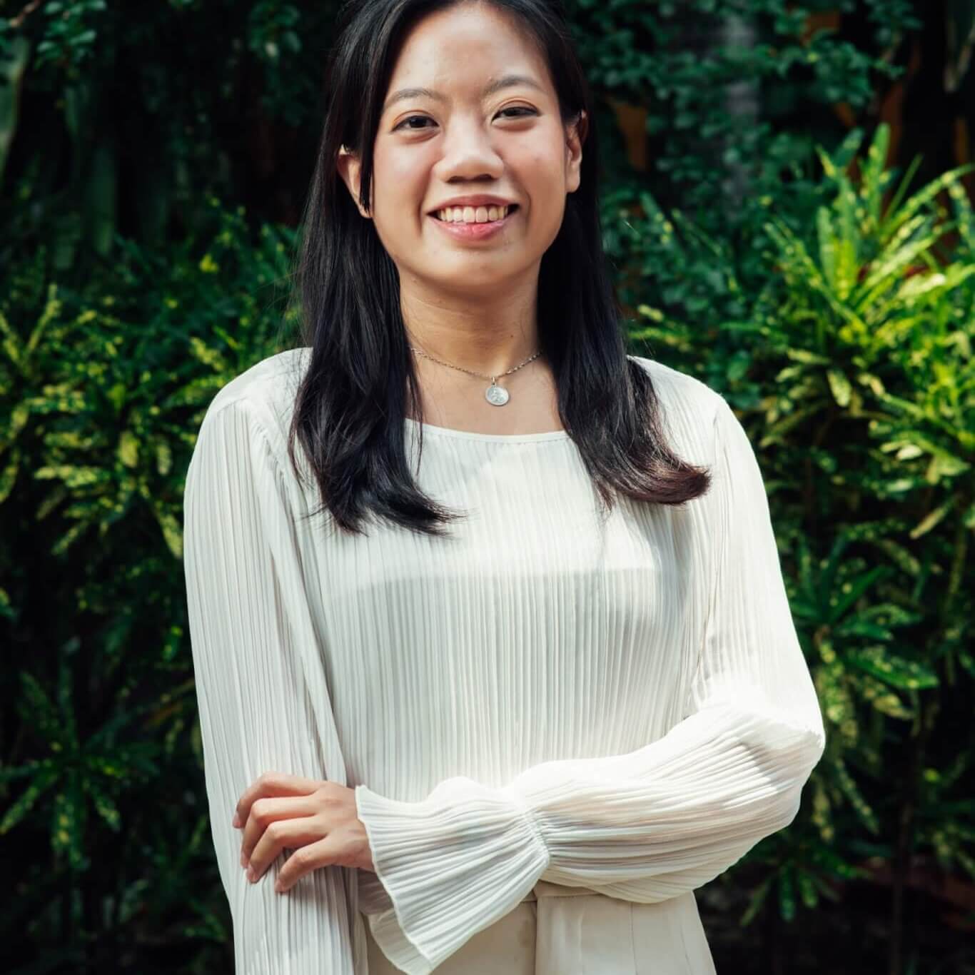 Concessa Angela Cheung, Psychologist based in Cebu City, smiling warmly while standing outdoors in front of green grass, conveying a compassionate and approachable presence in mental health services.